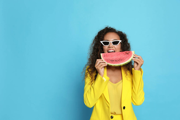 Beautiful young African American woman with watermelon on light blue background. Space for text - Fotoğraf, Görsel