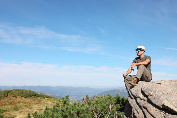 Man enjoying picturesque view on cliff in mountains. Space for text - Valokuva, kuva