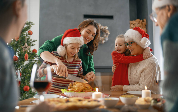 Merry Christmas. Happy family are having dinner at home. Celebration holiday and togetherness near tree. - Foto, Imagen