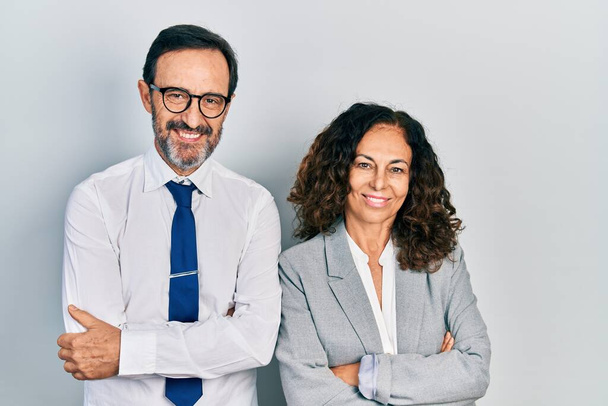 Middelbare leeftijd paar Latijns-Amerikaanse vrouwen en een man met een zakenkantoor uniform vrolijk gezicht glimlachend met gekruiste armen kijkend naar de camera. positieve persoon.  - Foto, afbeelding