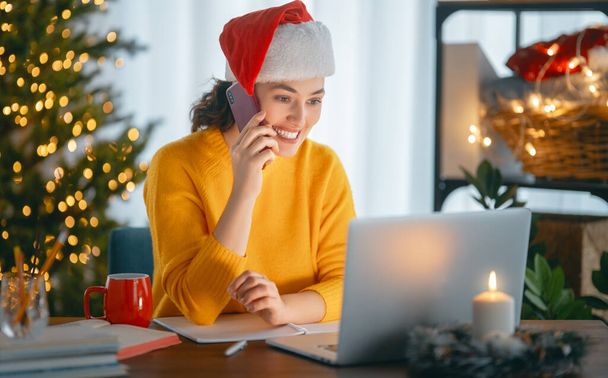 Woman is working in home office decorated for Christmas. - Φωτογραφία, εικόνα