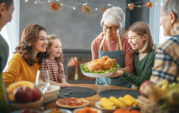 Thanksgiving Day, Autumn feast. Happy family sitting at the table and celebrating holiday. Grandparents, mother, father and children. Traditional dinner. - Фото, изображение