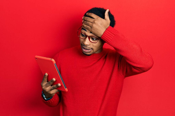 Young african american man using touchpad device stressed and frustrated with hand on head, surprised and angry face  - Fotoğraf, Görsel