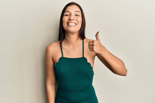 Young latin woman wearing casual clothes smiling happy and positive, thumb up doing excellent and approval sign  - Foto, immagini