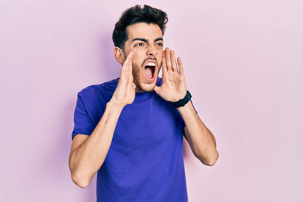 Gündelik tişört giyen genç İspanyol adam elleri ağızda bağırarak bağırıyor.  - Fotoğraf, Görsel