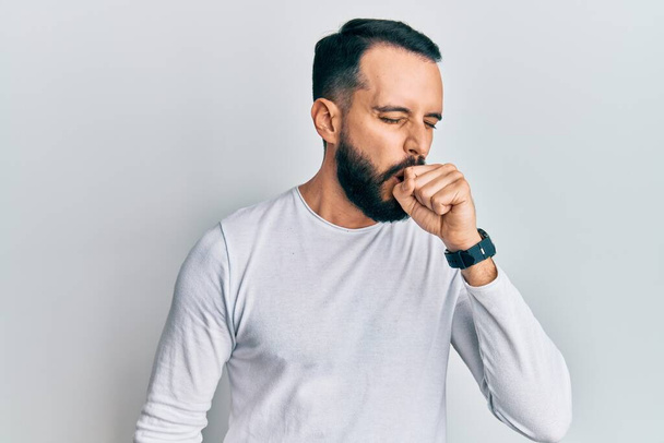 Young man with beard wearing casual white shirt feeling unwell and coughing as symptom for cold or bronchitis. health care concept.  - Foto, afbeelding