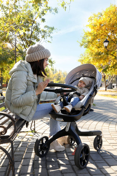 Happy mother with her baby son in stroller outdoors on autumn day - Fotoğraf, Görsel
