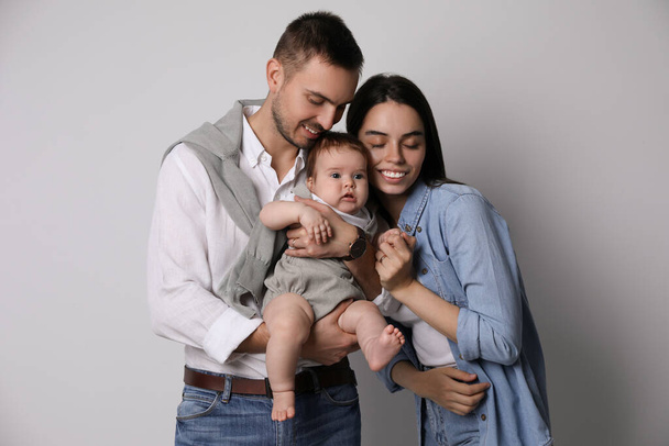 Happy family. Couple with their cute baby on grey background - Zdjęcie, obraz