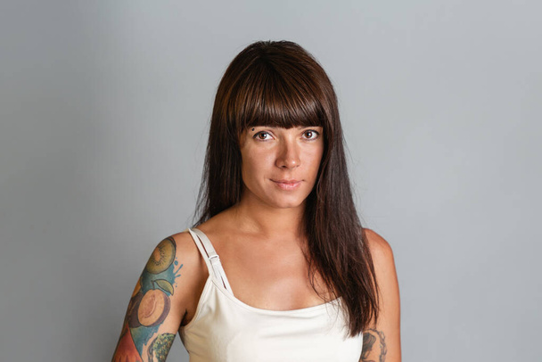 Portrait of a young tanned brunette woman with tattoos. Copy space. - Fotó, kép