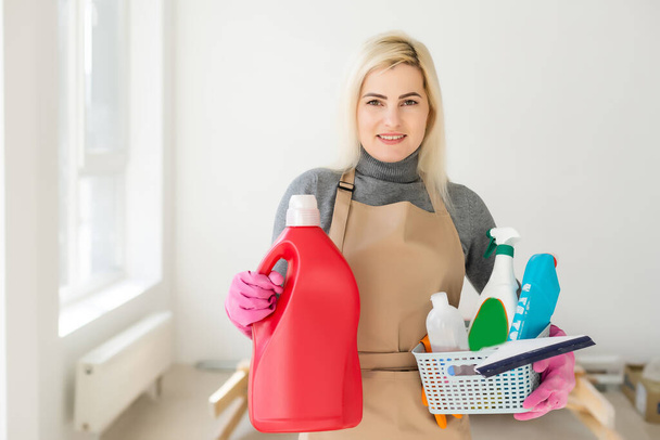 Servicio de limpieza concepto. Mujer joven con botella de detergente en la oficina
. - Foto, imagen