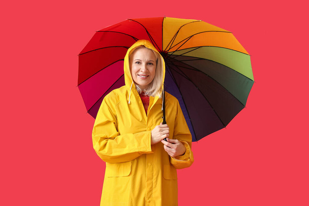 Mulher madura bonita em capa de chuva e com guarda-chuva no fundo de cor - Foto, Imagem