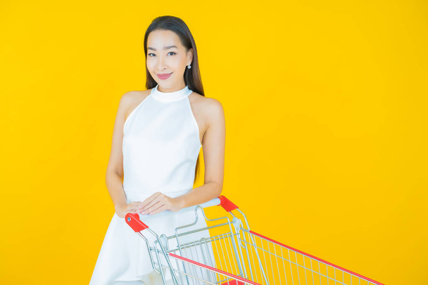 Ritratto bella giovane donna asiatica sorriso con cesto della spesa da supermercato su sfondo di colore - Foto, immagini