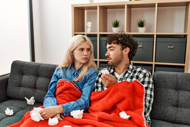 Young ill couple using napkin sititng on the sofa at home. - 写真・画像