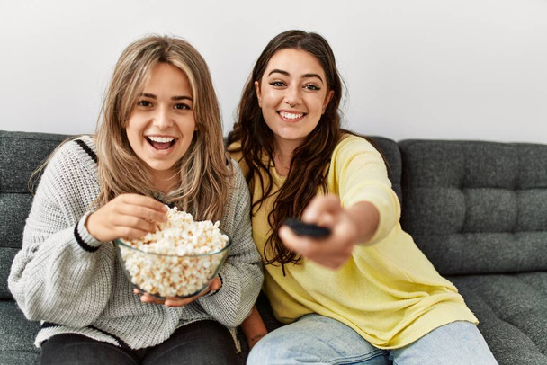 Young couple watching film and eating popcorn sitting on the sofa at home. - Foto, imagen
