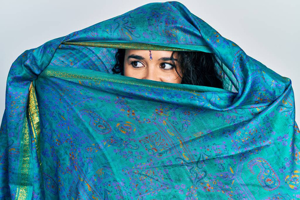 若いですインド人女性身に着けていますsariカバー頭と顔,伝統的なスカーフでエレガントなポーズをします - 写真・画像