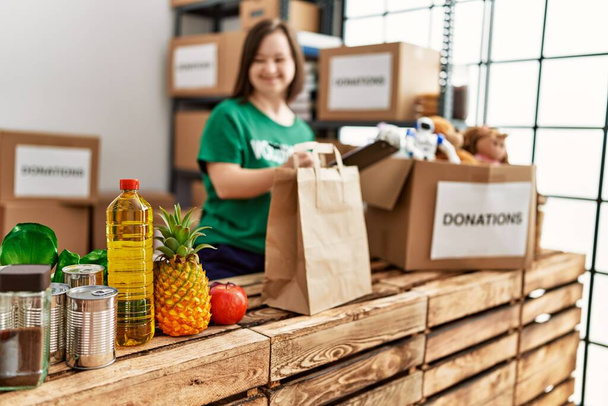 Brunette woman with down syndrome checking donated food at donations stand - Photo, Image
