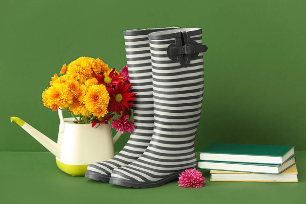 Composizione con stivali di gomma, fiori, annaffiatoio e libri su sfondo a colori - Foto, immagini