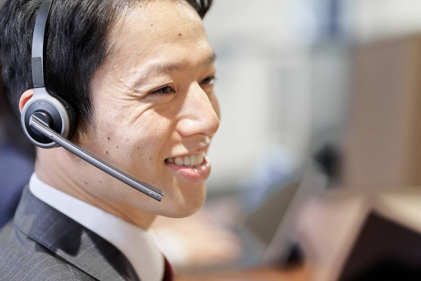 Azjatycki przedsiębiorca odpowiadający w centrum obsługi klienta - Zdjęcie, obraz
