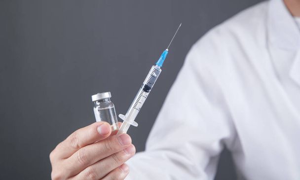 Medical doctor holds syringe and vaccine. - Φωτογραφία, εικόνα