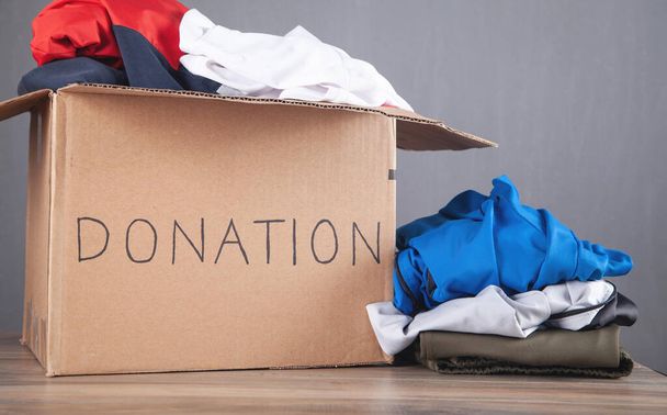 Spendenbox mit Kleidung auf dem Holztisch. - Foto, Bild