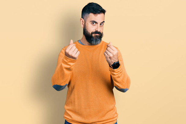 Hispanic man with beard wearing casual winter sweater doing money gesture with hands, asking for salary payment, millionaire business  - Foto, imagen