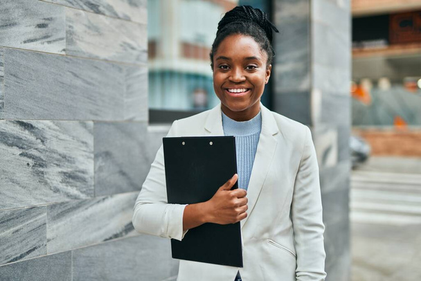 Young african american businesswoman smiling happy holding clipboard at the city. - Fotografie, Obrázek
