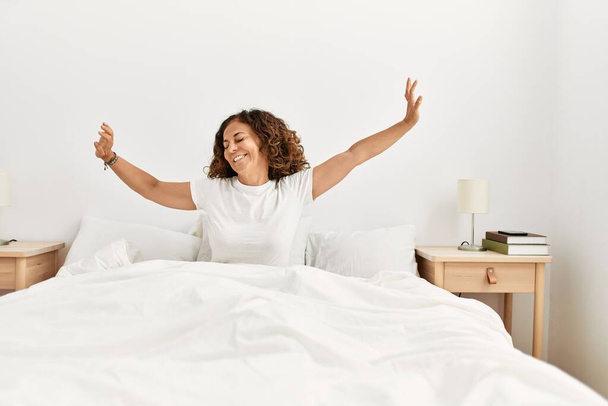 Middle age hispanic woman smiling confident waking up at bedroom - Photo, Image