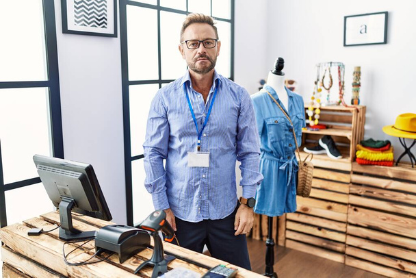 Middle age man working as manager at retail boutique relaxed with serious expression on face. simple and natural looking at the camera.  - Foto, immagini
