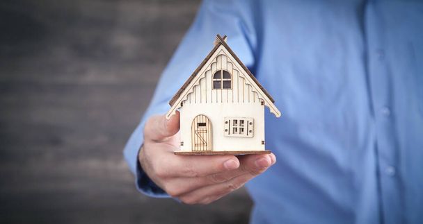 Real estate agent holding wooden house model. - Φωτογραφία, εικόνα