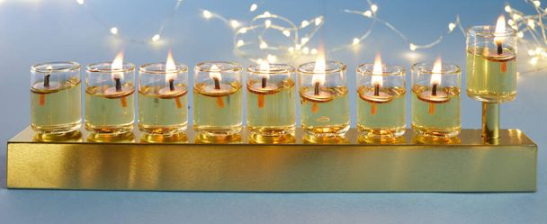 Jewish holiday Hanukkah background with menorah traditional candelabra and candles on blue background - Fotó, kép
