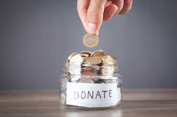 Male hand putting coin into Donation jar. - Foto, imagen