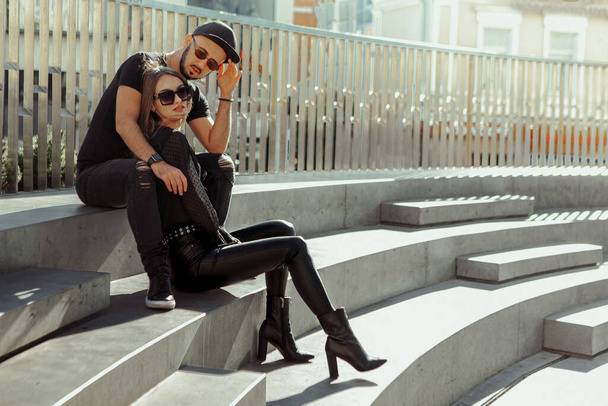 Beautiful couple sits on the stairs in the street and hugs - Zdjęcie, obraz