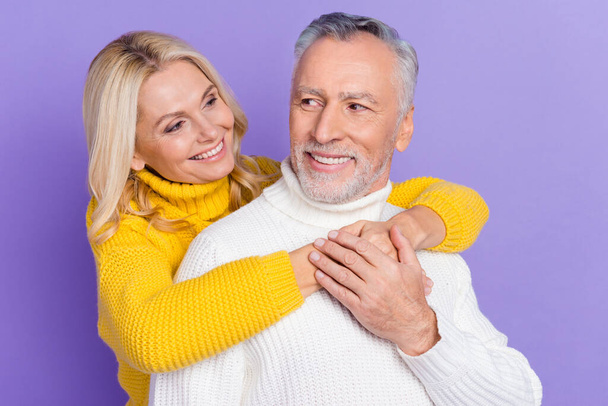 Photo of adorable cute mature wife husband wear knitted pullovers smiling embracing looking eyes isolated purple color background - Фото, зображення