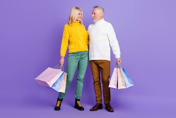 Foto van charmante schattige senior echtgenoot vrouw gekleed breigoed truien knuffelen met winkelen dag geïsoleerde violette kleur achtergrond - Foto, afbeelding