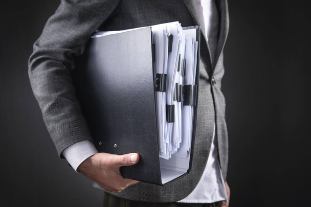 Caucasian businessman holding documents in office. - Фото, изображение