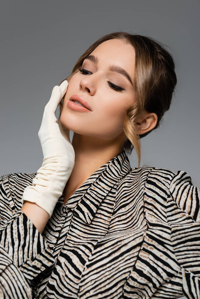 pretty woman in blouse with animal print and white glove posing isolated on grey - Фото, изображение