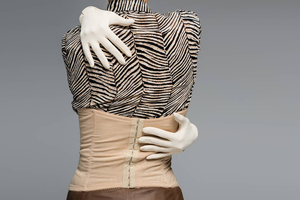 przycięty widok modnej kobiety w bluzce z nadrukiem zwierzęcia, rękawiczki i gorset obejmujący się odizolowany na szarości - Zdjęcie, obraz