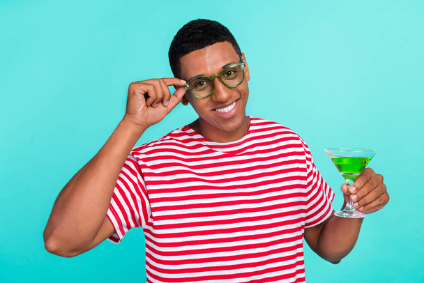 Foto van grappige mooie jonge man gekleed rood t-shirt drinken drank glimlachen geïsoleerde turquoise kleur achtergrond - Foto, afbeelding