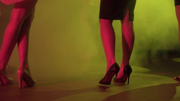 Jonge dames op hoge hakken dansen in nachtclub tussen de rook en licht show - Video
