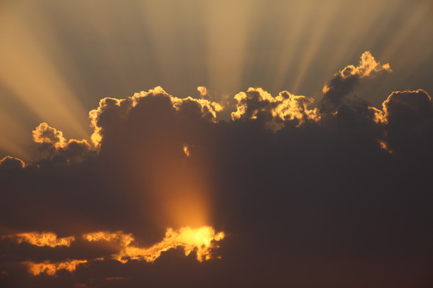 de stralen van de zon door de wolken bij zonsondergang - Foto, afbeelding