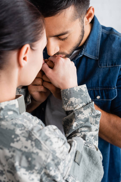 Man kissing hand of wife in military uniform at home  - Foto, Imagen