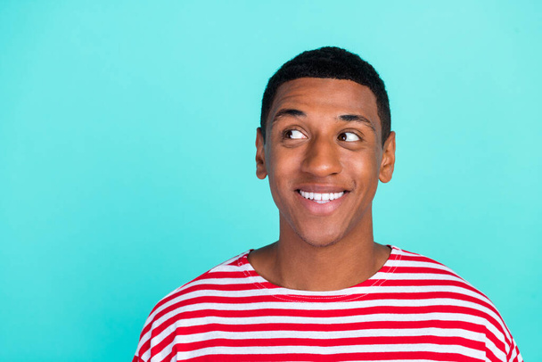 Photo of pretty funky young man wear striped t-shirt smiling looking empty space isolated teal color background - Photo, Image