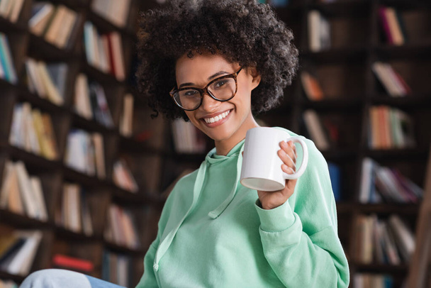 vrolijk Afrikaans amerikaanse vrouw in bril met kopje koffie  - Foto, afbeelding