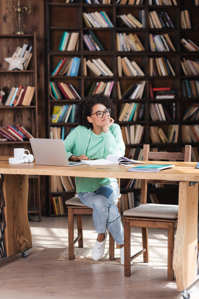 Étudiant afro-américain coûteux en lunettes étudiant en ligne près d'un ordinateur portable  - Photo, image