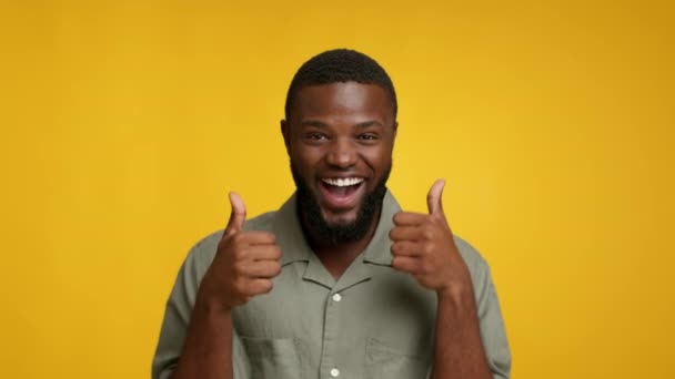 I Like It. Overjoyed Black Guy Showing Thumbs Up At Camera, Cheerful Playful African American Man Dancing While Showing Sign Of Approval, Posing Over Yellow Studio Background, Slow Motion Footage - Footage, Video