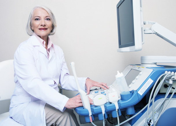 Médecin senior souriant lors de la mise en place de la machine à ultrasons
 - Photo, image