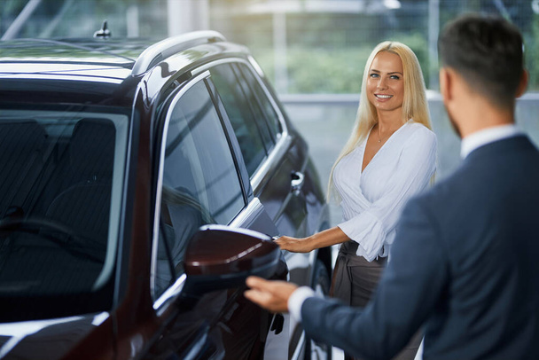 Manager helping female customer choosing new car at salon - 写真・画像