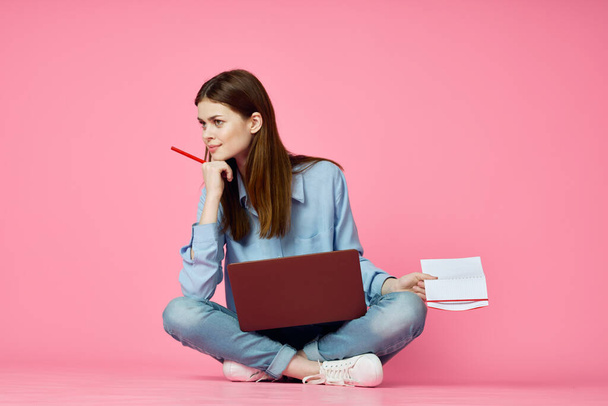woman sitting on floor with laptop shopping entertainment pink background - Foto, immagini