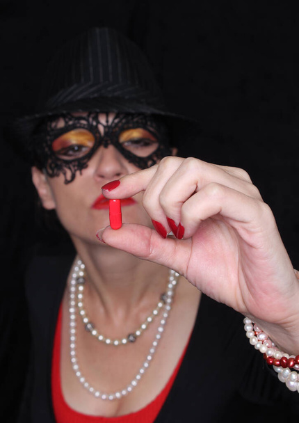Woman in mask and fedora holding red pill - Foto, immagini