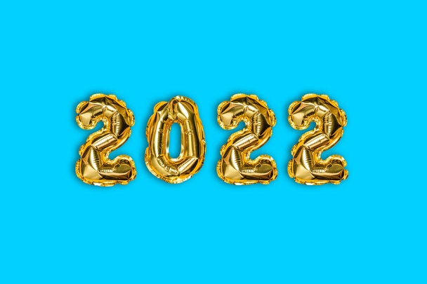 2022 goldene Folienballons und Weihnachtsschnee mit Kopierraum auf blauem Hintergrund. Neujahrskonzept - Foto, Bild